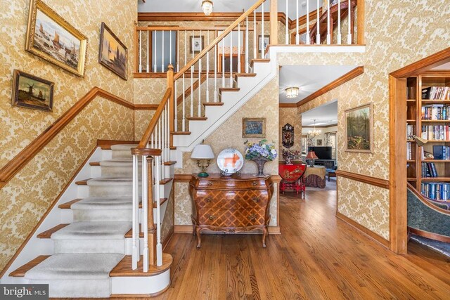 8413 Pathfinders Ct, Spotsylvania, VA 22553 - stairway featuring ornamental molding, wallpapered walls, a high ceiling, and wood finished floors