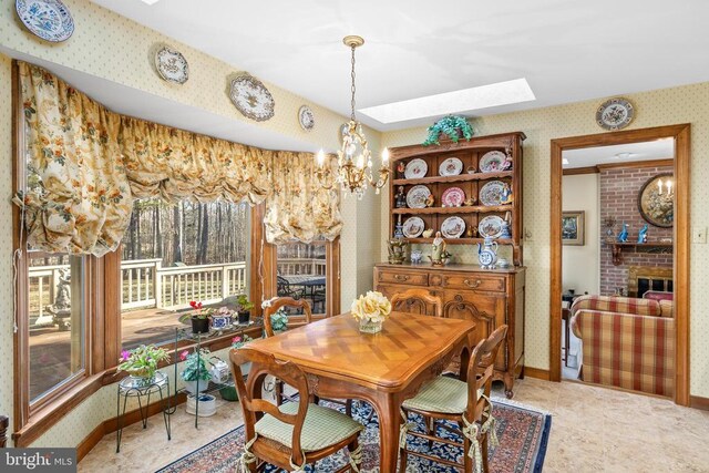 8413 Pathfinders Ct, Spotsylvania, VA 22553 - dining space featuring wallpapered walls, a fireplace, a skylight, baseboards, and a chandelier