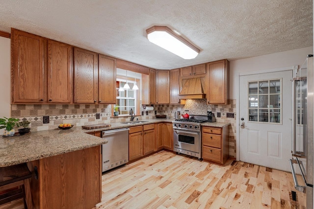 4201 Brown Mountain Ln, Elkton, VA 22827 - kitchen with appliances with stainless steel finishes, a textured ceiling, brown cabinets, a peninsula, and light wood finished floors