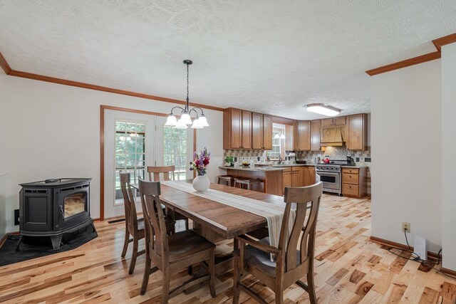 4201 Brown Mountain Ln, Elkton, VA 22827 - dining room featuring light wood-style flooring, a wood stove, crown molding, a textured ceiling, and a chandelier