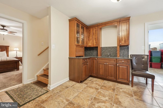12011 Big Ben Blvd, Fredericksburg, VA 22407 - kitchen with brown cabinetry, decorative backsplash, stone tile flooring, and dark stone counters