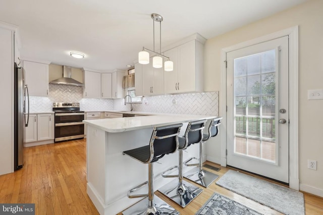 12011 Big Ben Blvd, Fredericksburg, VA 22407 - kitchen featuring appliances with stainless steel finishes, wall chimney range hood, a peninsula, tasteful backsplash, and light countertops