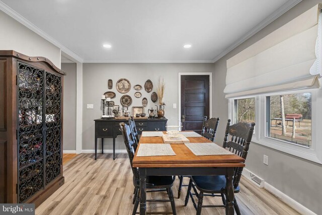 dining area with crown molding and light hardwood / wood-style flooring