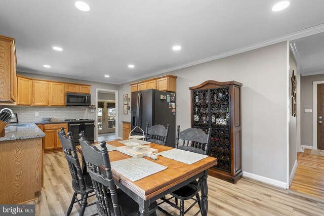 dining room with crown molding, sink, and light wood-type flooring