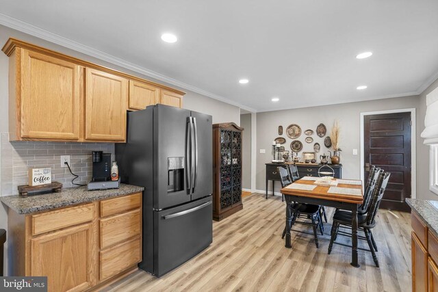 kitchen featuring stone counters, ornamental molding, stainless steel fridge, and light wood-type flooring