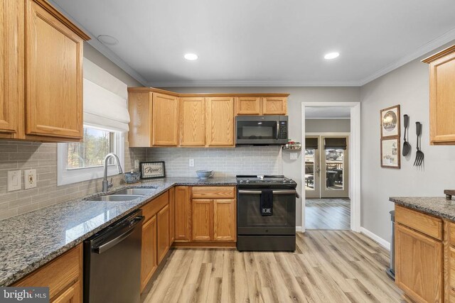 kitchen with sink, light stone counters, ornamental molding, black appliances, and light wood-type flooring