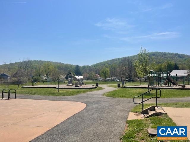 view of home's community with playground community, a view of trees, and a lawn