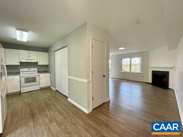 kitchen featuring baseboards, under cabinet range hood, dark wood-style floors, white cabinets, and white range with electric stovetop