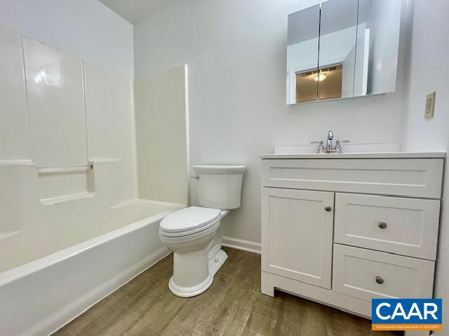 bathroom featuring toilet, baseboards, vanity, wood finished floors, and shower / bathing tub combination