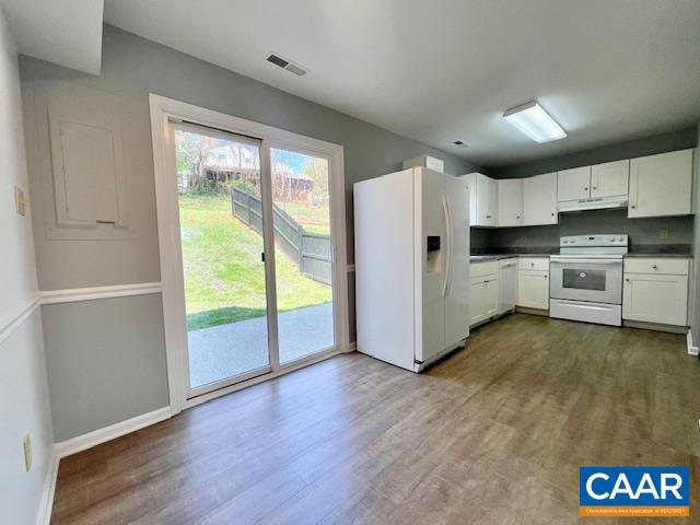 kitchen featuring under cabinet range hood, white appliances, dark wood-style floors, and visible vents