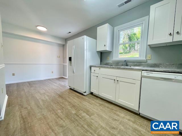 kitchen featuring a sink, white cabinets, visible vents, white appliances, and light wood-style floors