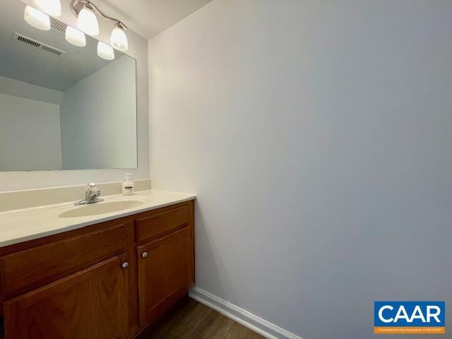 bathroom featuring vanity, baseboards, visible vents, and wood finished floors