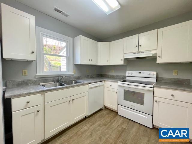 kitchen with a sink, light wood-type flooring, visible vents, white appliances, and under cabinet range hood