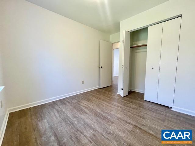 unfurnished bedroom with a closet, wood finished floors, and baseboards