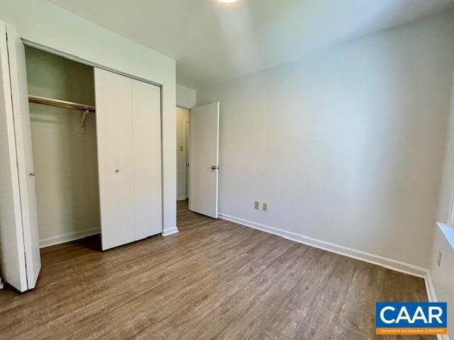 unfurnished bedroom featuring a closet, wood finished floors, and baseboards