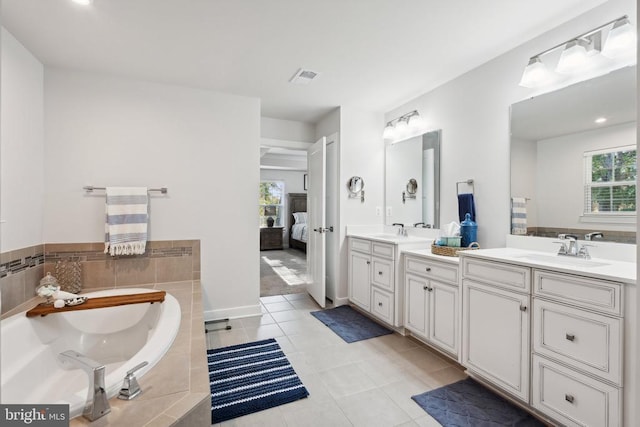 ensuite bathroom with double vanity, tile patterned flooring, a garden tub, and recessed lighting