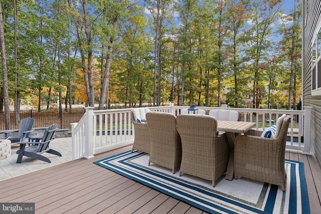 wooden terrace featuring outdoor dining area, fence, and view of scattered trees