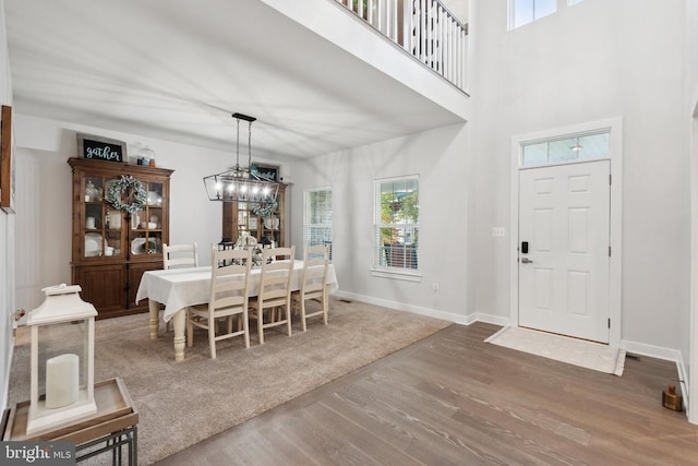 dining space featuring wood finished floors, plenty of natural light, baseboards, and a chandelier