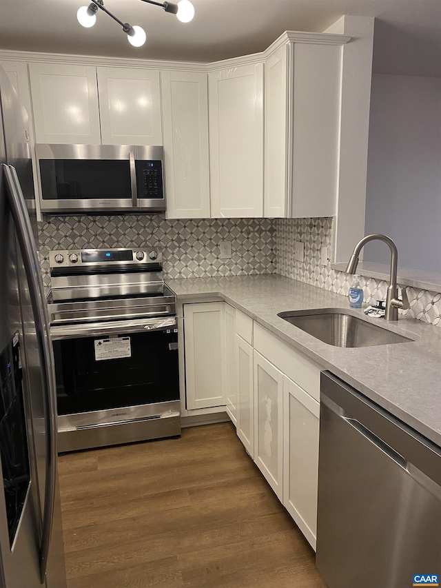 kitchen with a sink, stainless steel appliances, white cabinetry, light countertops, and backsplash