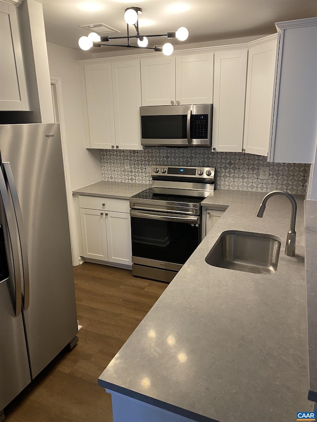 kitchen with a sink, dark wood-type flooring, decorative backsplash, white cabinets, and appliances with stainless steel finishes