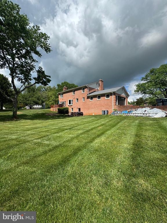 7880 Sir Topas Dr, Warrenton, VA 20186 - rear view of house featuring a chimney, a lawn, and brick siding