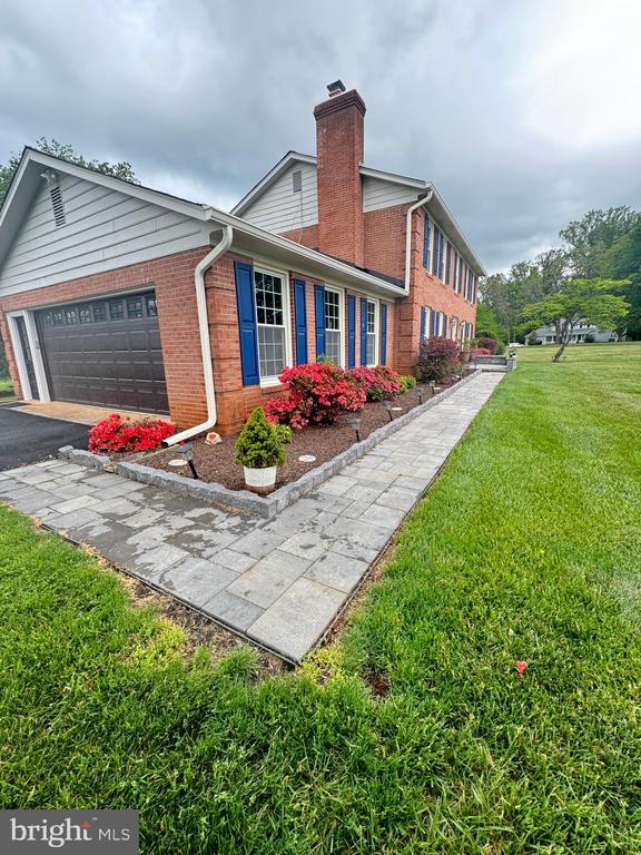7880 Sir Topas Dr, Warrenton, VA 20186 - view of side of property featuring brick siding, a chimney, a yard, an attached garage, and driveway