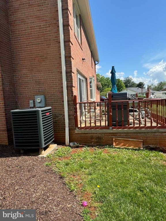 7880 Sir Topas Dr, Warrenton, VA 20186 - view of side of property with cooling unit, a deck, brick siding, and a lawn