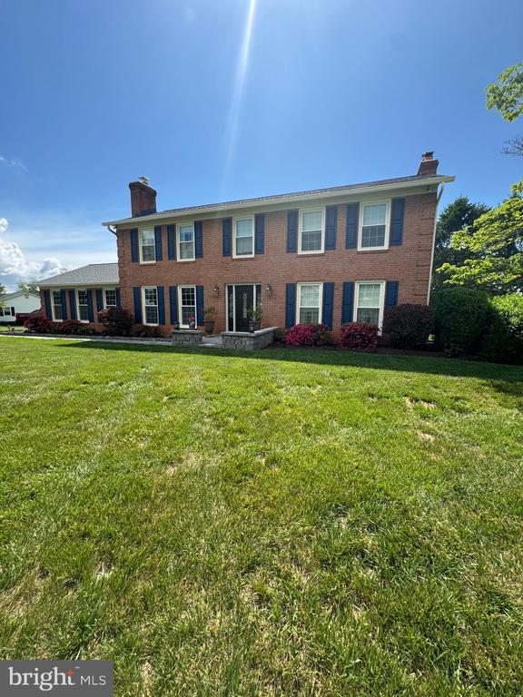 7880 Sir Topas Dr, Warrenton, VA 20186 - colonial-style house with a chimney, brick siding, and a front lawn
