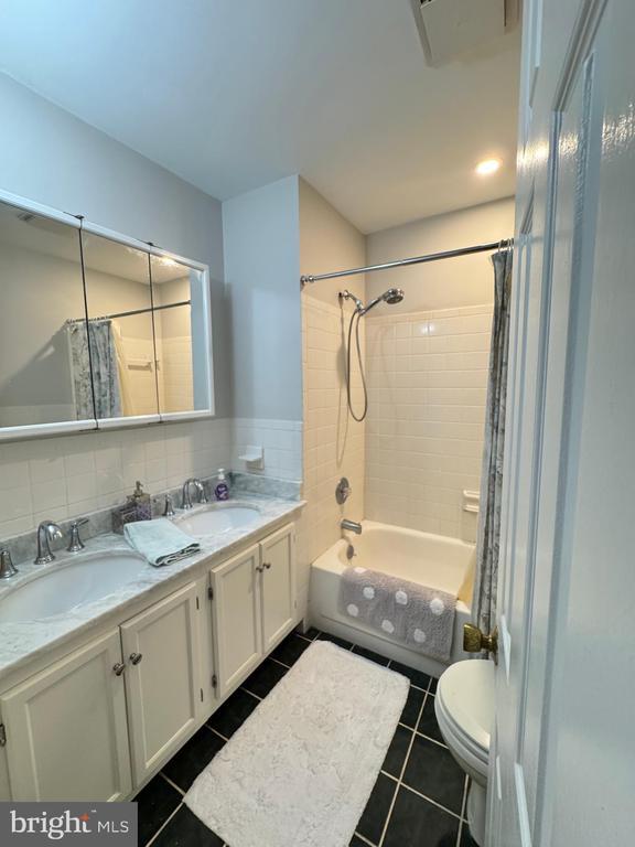 7880 Sir Topas Dr, Warrenton, VA 20186 - bathroom featuring double vanity, shower / bath combination with curtain, tile patterned floors, and toilet