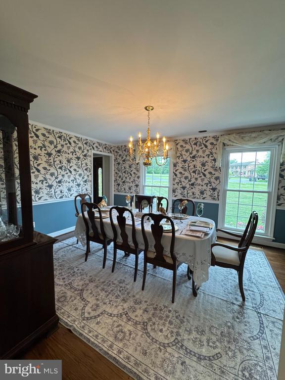 7880 Sir Topas Dr, Warrenton, VA 20186 - dining space with wallpapered walls, a chandelier, wainscoting, and dark wood-style flooring