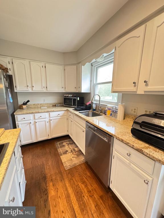 7880 Sir Topas Dr, Warrenton, VA 20186 - kitchen with stainless steel appliances, a sink, white cabinets, and dark wood-style floors