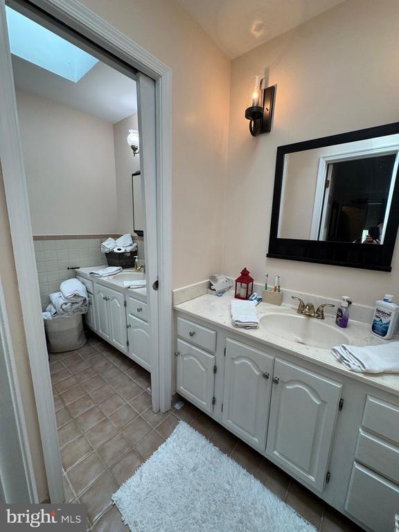 7880 Sir Topas Dr, Warrenton, VA 20186 - bathroom with tile patterned floors, vanity, a skylight, tile walls, and wainscoting