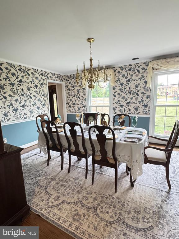 7880 Sir Topas Dr, Warrenton, VA 20186 - dining space featuring wallpapered walls, a chandelier, healthy amount of natural light, wood finished floors, and a wainscoted wall