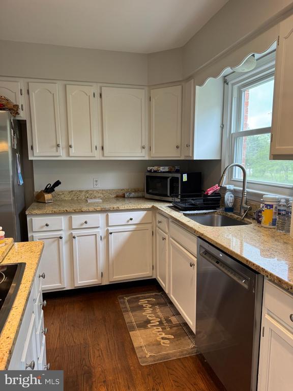 7880 Sir Topas Dr, Warrenton, VA 20186 - kitchen featuring appliances with stainless steel finishes, a sink, white cabinetry, dark wood-style floors, and light stone countertops