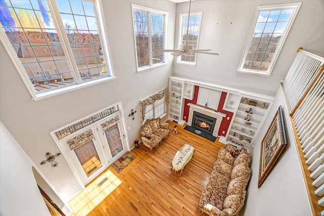 102 Shawn Cir, Staunton, VA 24401 - living area with a warm lit fireplace, wood finished floors, a towering ceiling, a healthy amount of sunlight, and a ceiling fan