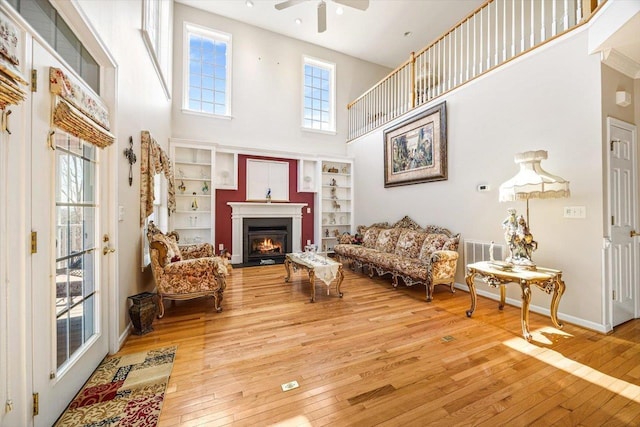 102 Shawn Cir, Staunton, VA 24401 - living area featuring a ceiling fan, baseboards, a towering ceiling, a warm lit fireplace, and hardwood / wood-style flooring