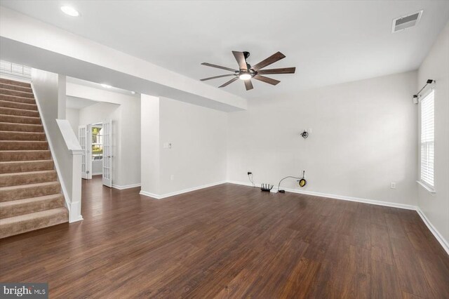 unfurnished living room featuring a ceiling fan, baseboards, visible vents, dark wood-style floors, and stairway