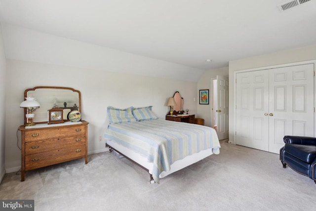 carpeted bedroom with a closet, lofted ceiling, and baseboards