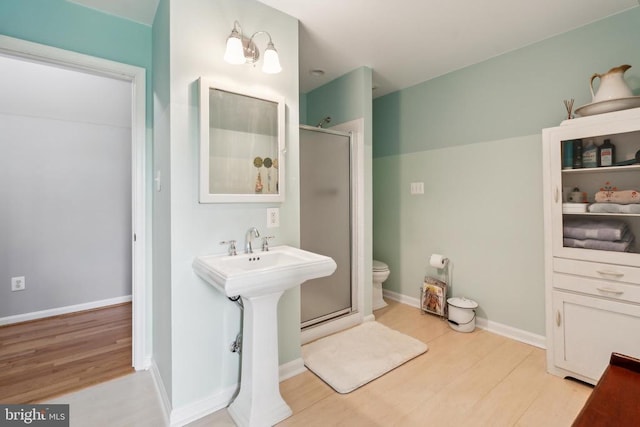 bathroom with wood finished floors, a shower stall, and toilet