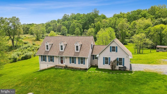 cape cod house featuring a front yard and a wooded view
