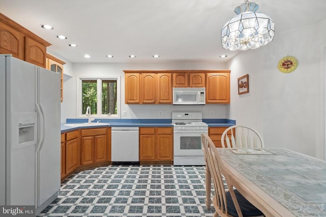  - kitchen featuring white appliances, recessed lighting, brown cabinetry, decorative light fixtures, and a chandelier