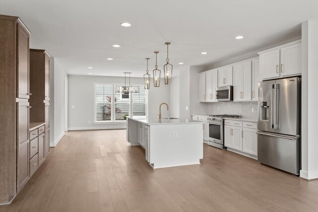 3251 Preston Shore Dr Unit 18E, Rockingham, VA 22801 - kitchen featuring premium appliances, light countertops, a kitchen island with sink, wood finished floors, and decorative backsplash