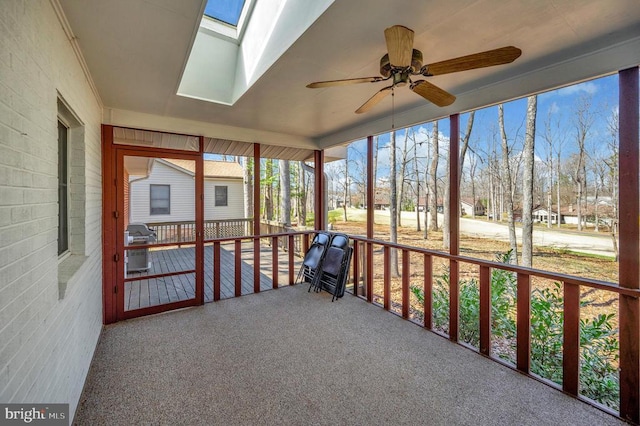 unfurnished sunroom featuring a ceiling fan and a skylight