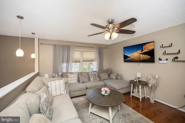 living area featuring a ceiling fan, baseboards, and wood finished floors