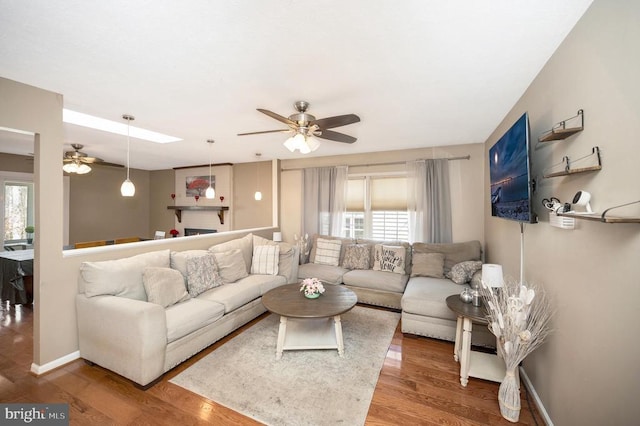 living area featuring a ceiling fan, plenty of natural light, and wood finished floors
