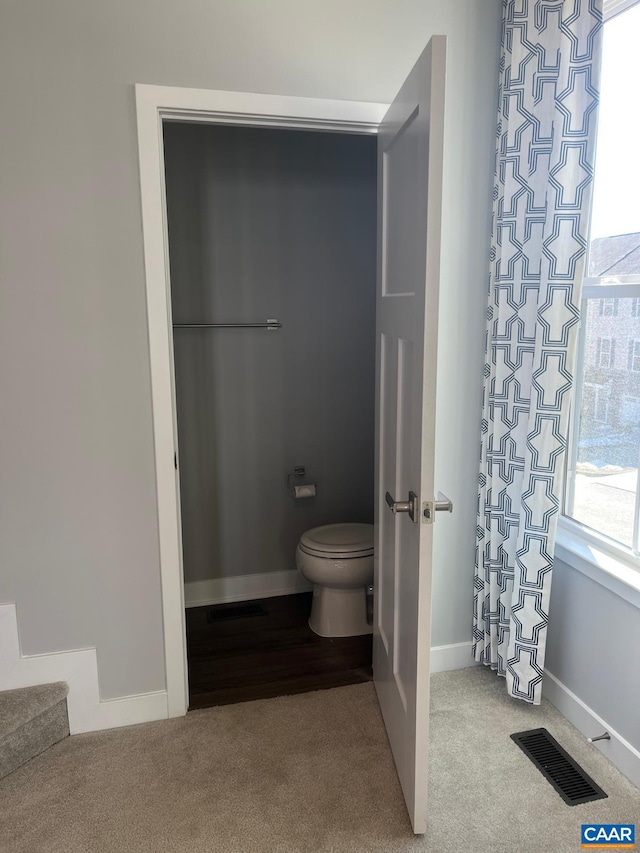 bathroom featuring toilet, visible vents, and baseboards