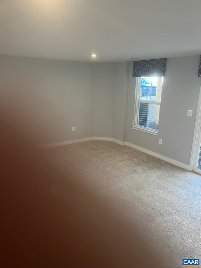 carpeted empty room featuring baseboards