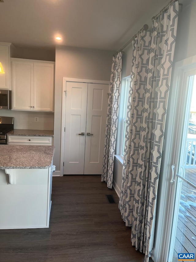 kitchen featuring dark wood finished floors, visible vents, white cabinetry, light stone countertops, and appliances with stainless steel finishes