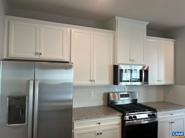 kitchen with light stone countertops, stainless steel appliances, tasteful backsplash, and white cabinets