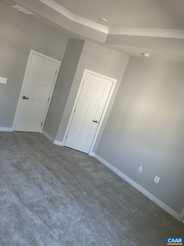 spare room with a tray ceiling, carpet flooring, and baseboards